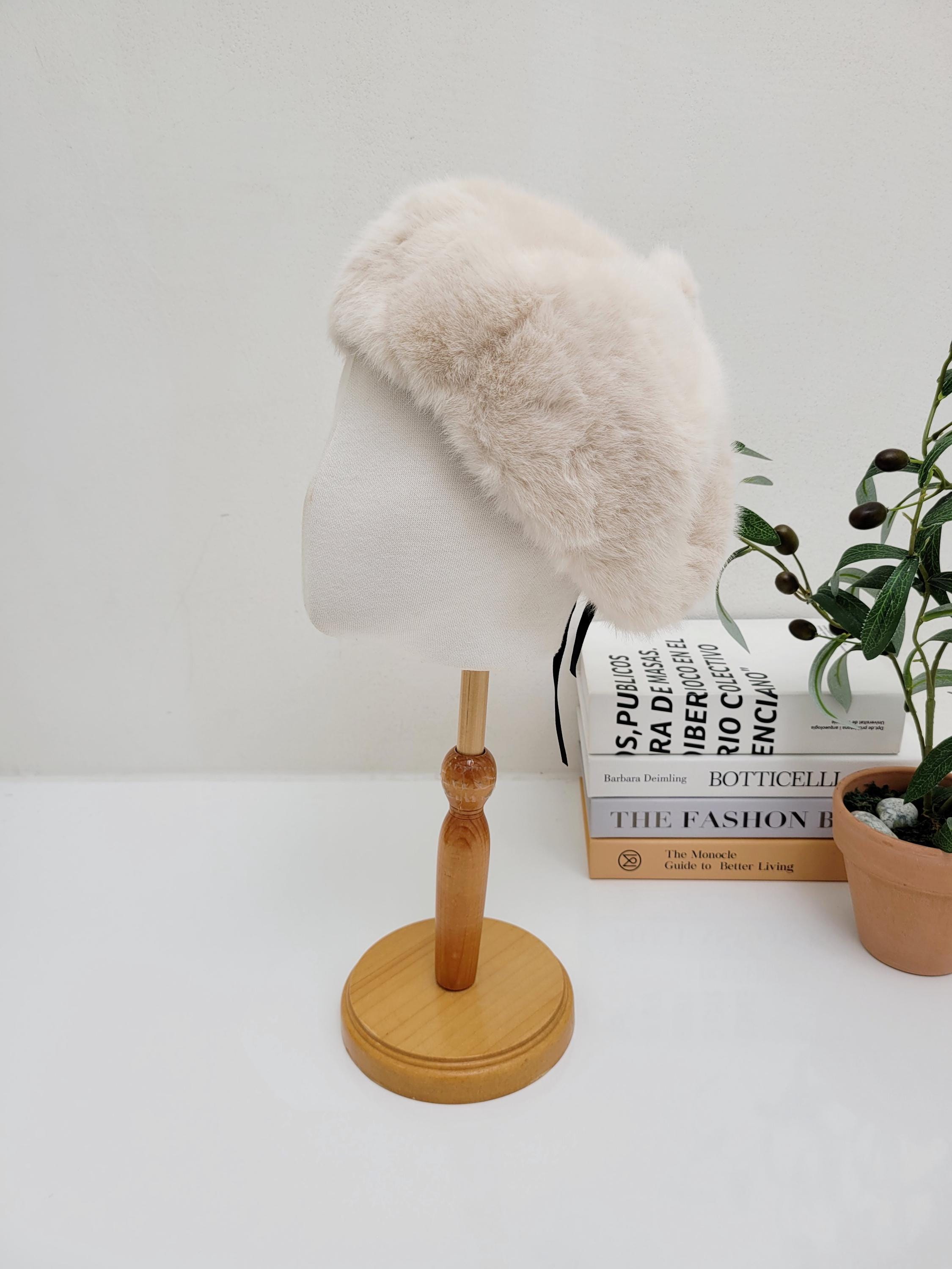 paris in winter faux fur hat, light beige, displayed on a mannequin. Soft and warm winter accessory.
