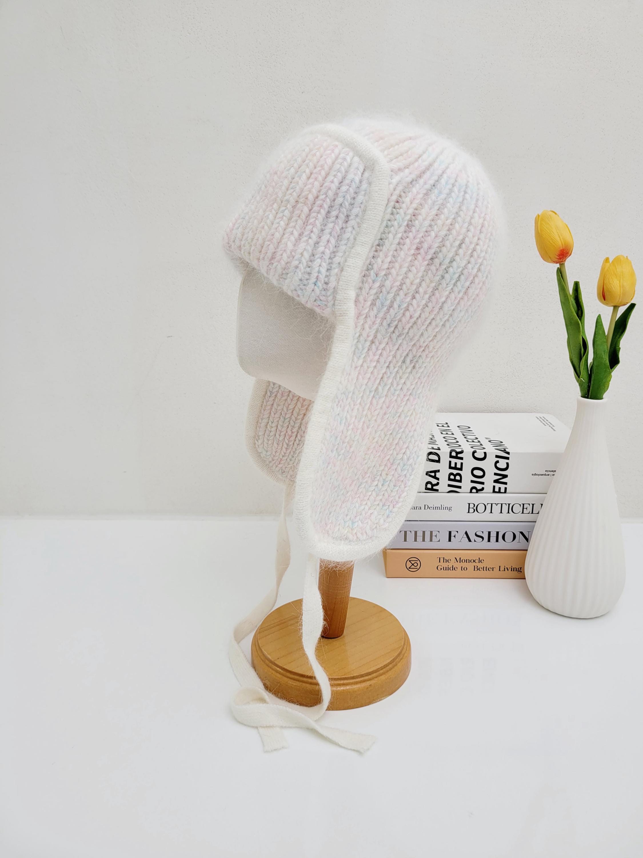 Soft, white angora trapper hat, the west mountain angora trapper hat features ear flaps with tie strings, and subtle pastel color accents.