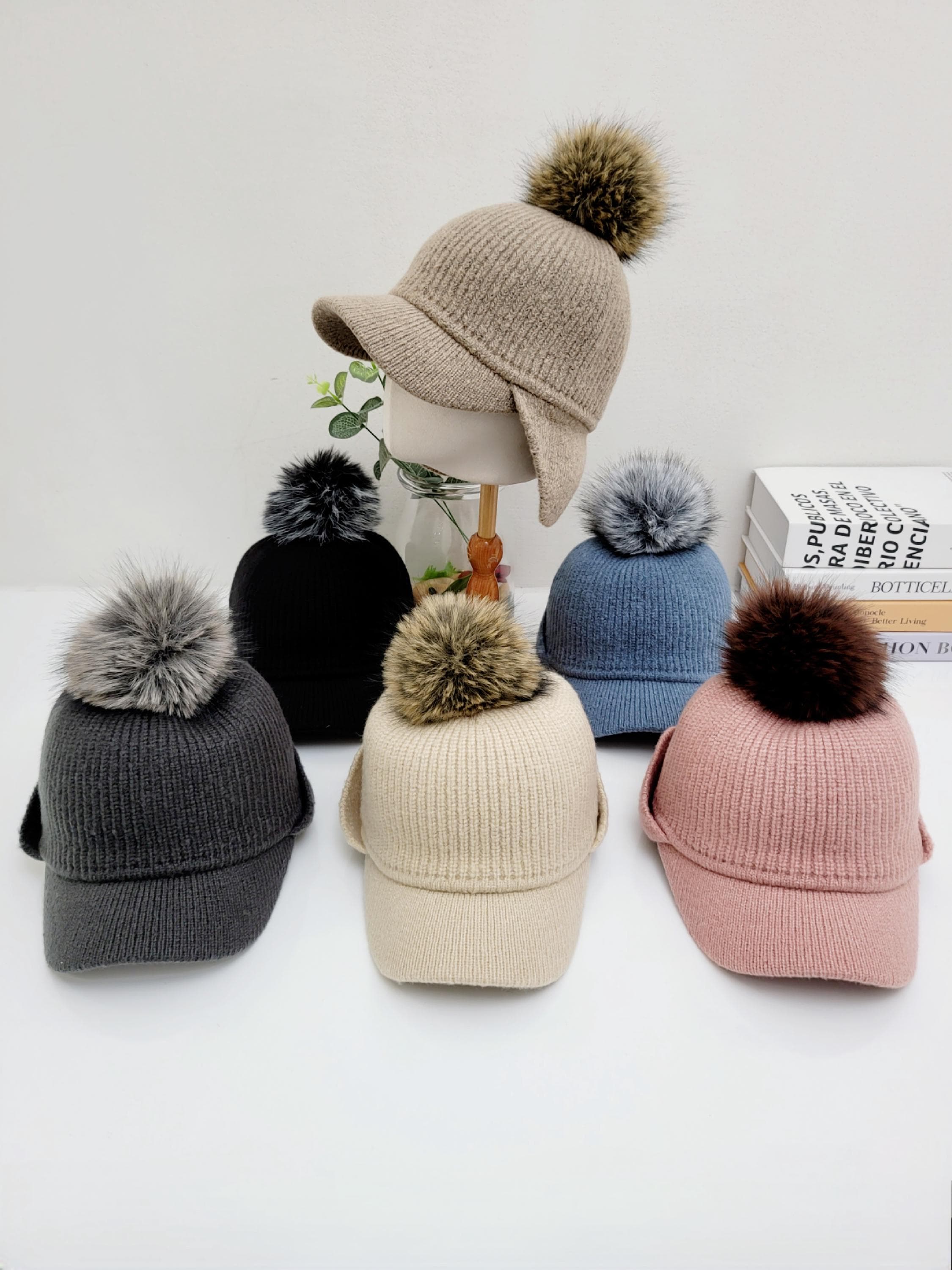 Six ribbed cap - pom hats in beige, black, gray, cream, blue, and pink. Knit caps with visors and faux fur pom-poms.
