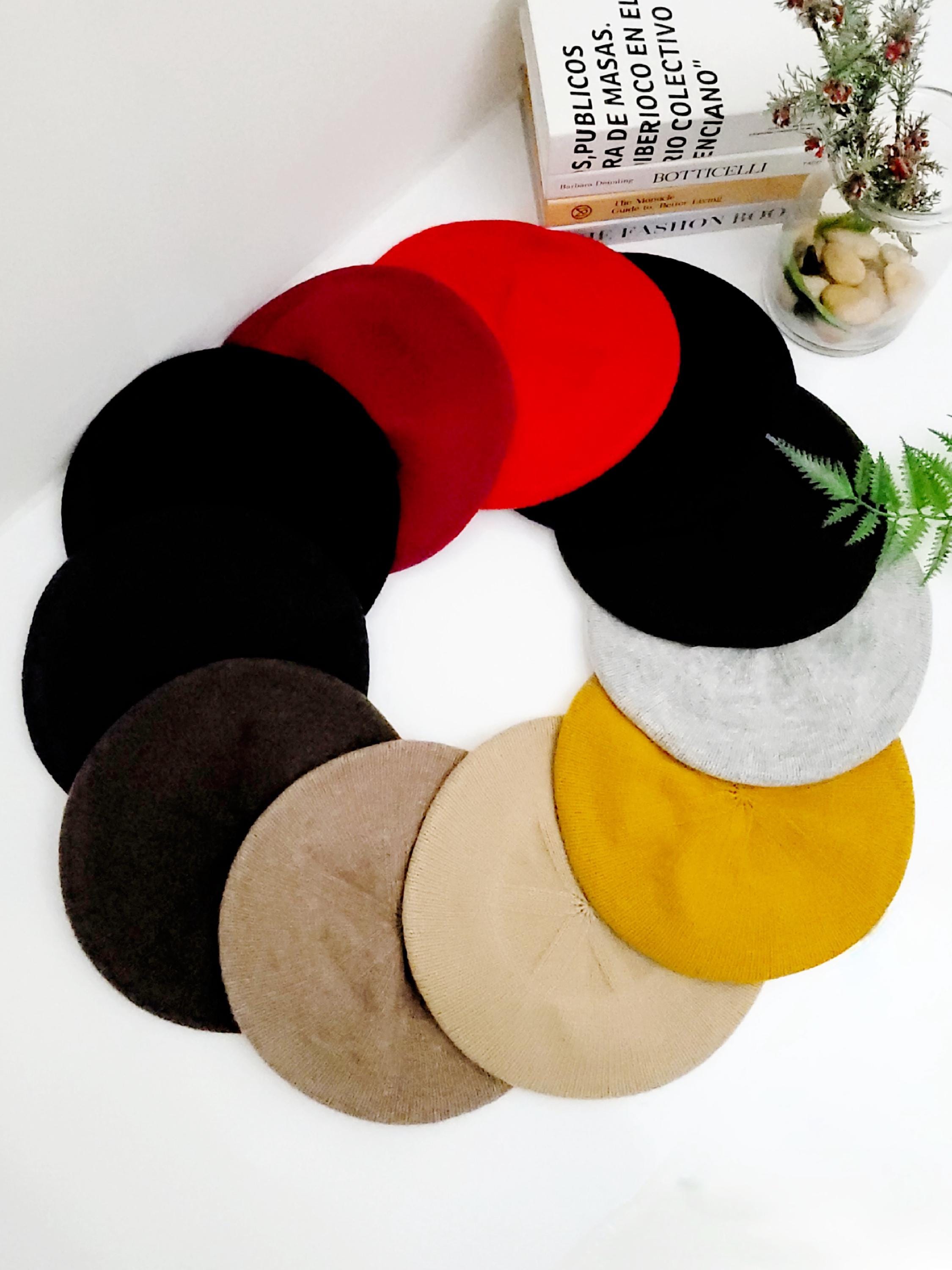 A colorful assortment of berets stacked together, showcasing various shades and styles.