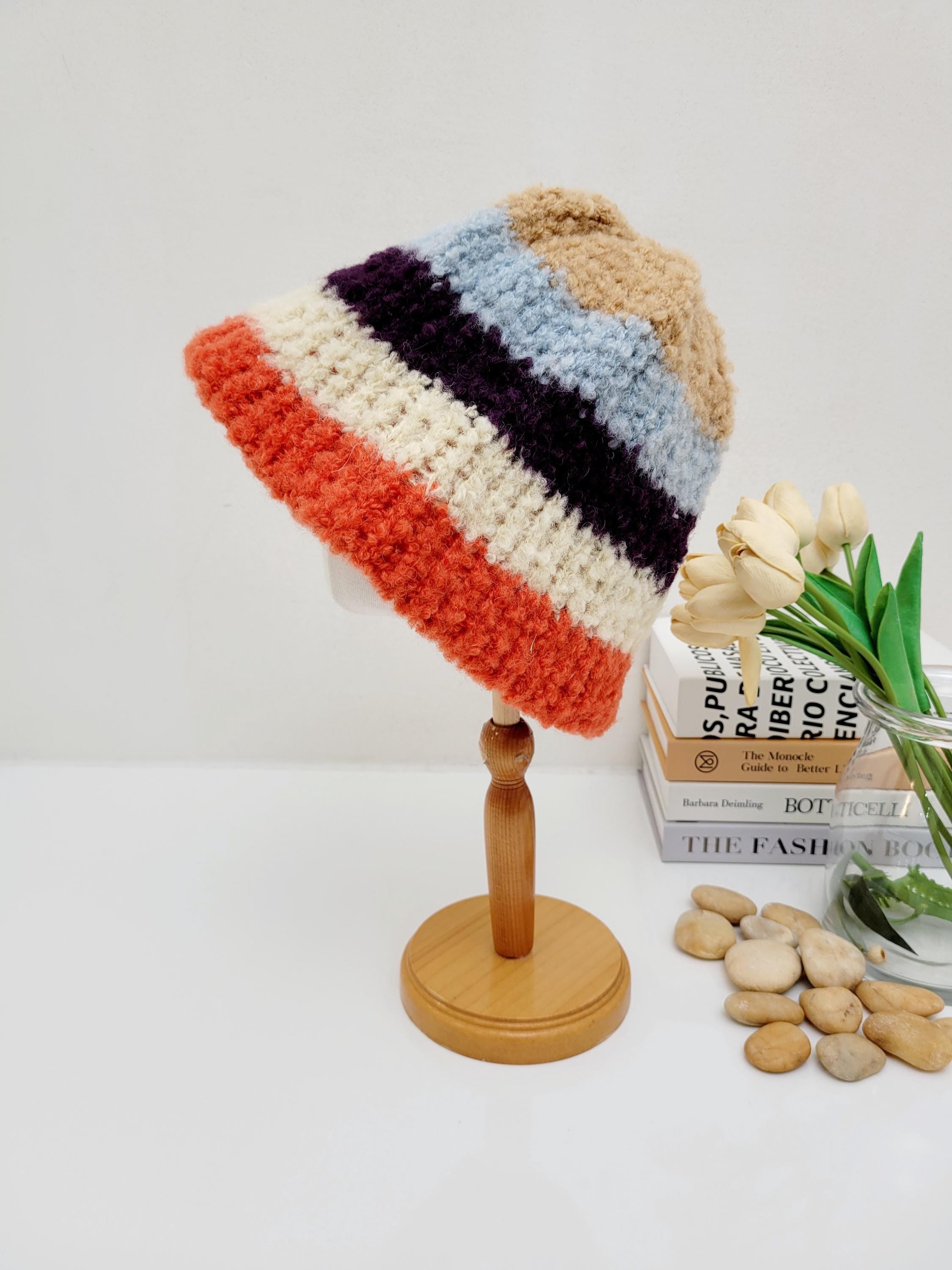 Striped tokyo beanie - stripe bucket hat on a wooden stand. Multicolored with orange, cream, purple, light blue, and tan stripes. Cozy, stylish, and handmade.