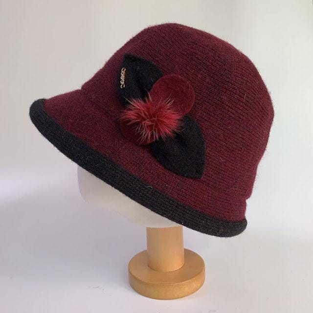 Burgundy knit cloche hat from linda's favorite, featuring a black brim, decorative leaf, and burgundy pompom detail.