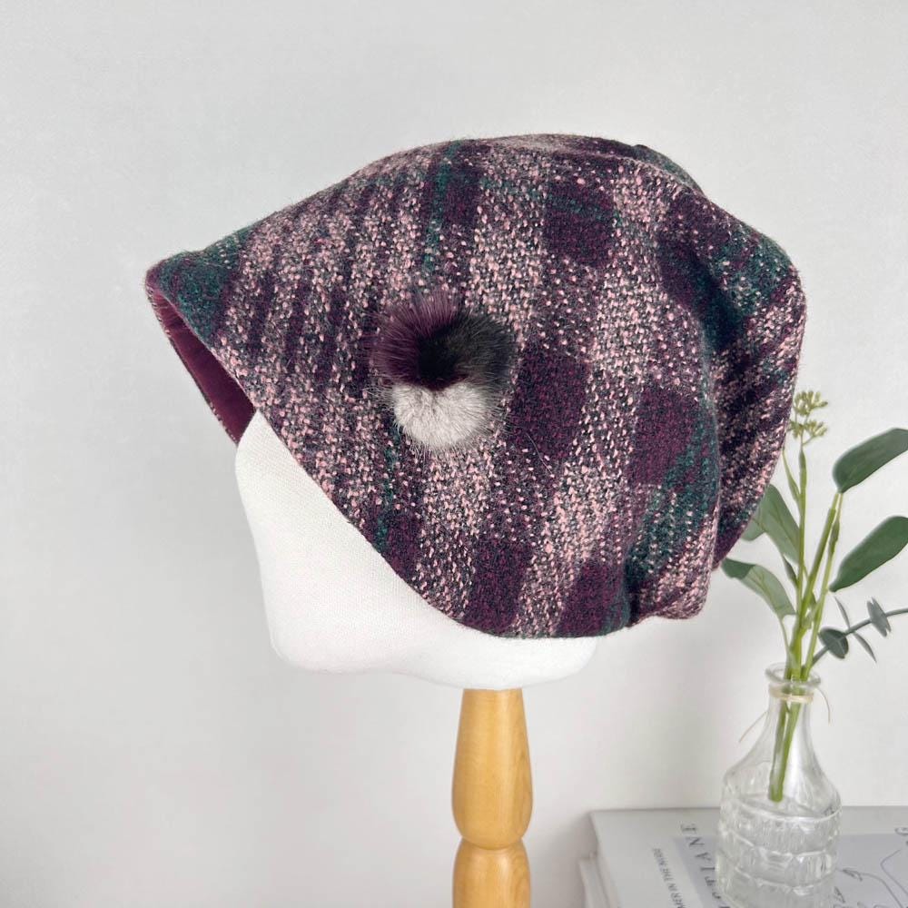 
CHEKERED SLOUCH hat: Plaid beret in purple, pink, and green tweed with a fluffy pom-pom detail. Stylish and cozy winter headwear.
