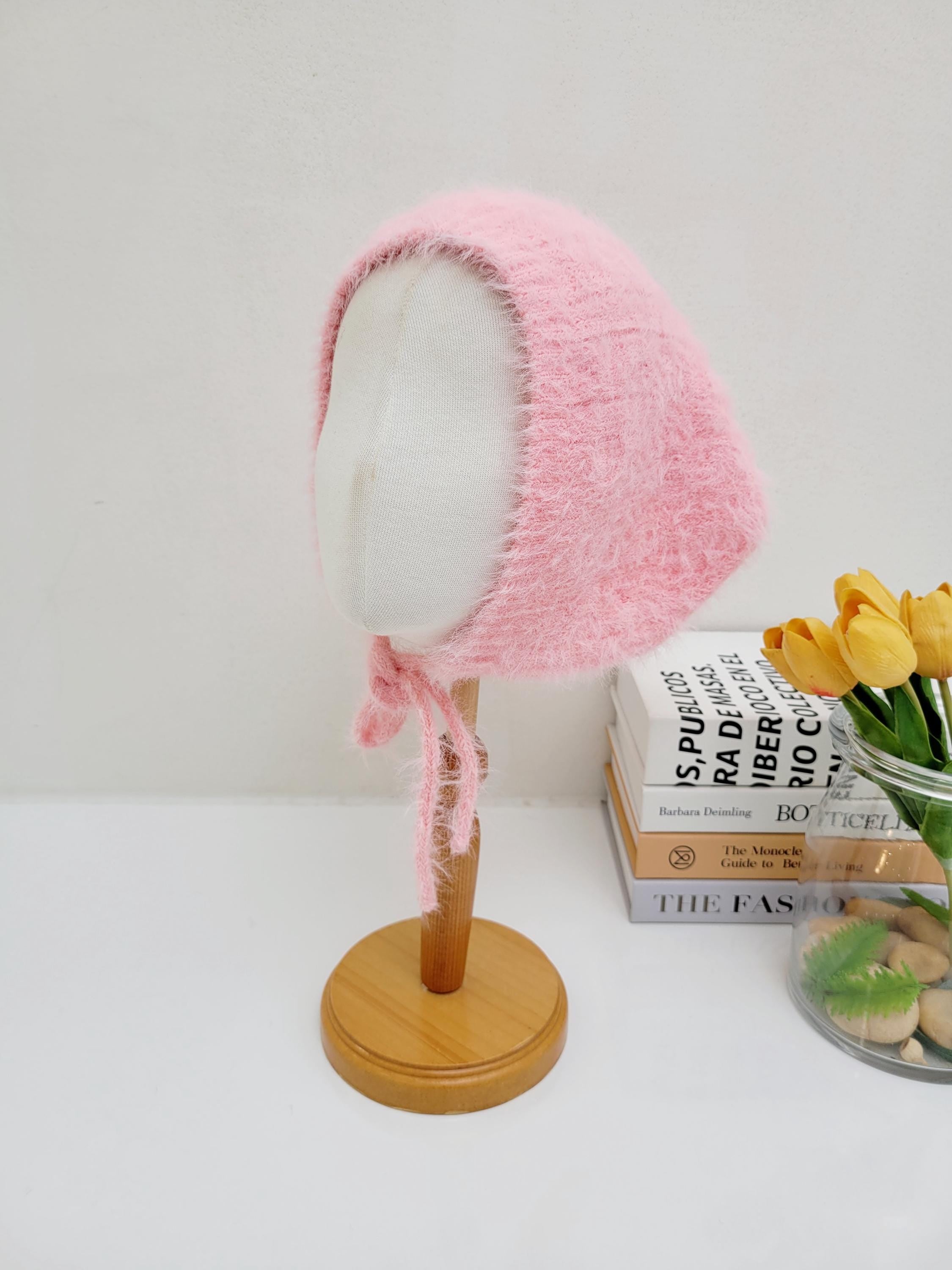Pink fuzzy little riding hood bonnet with tie strings, displayed on a mannequin head.