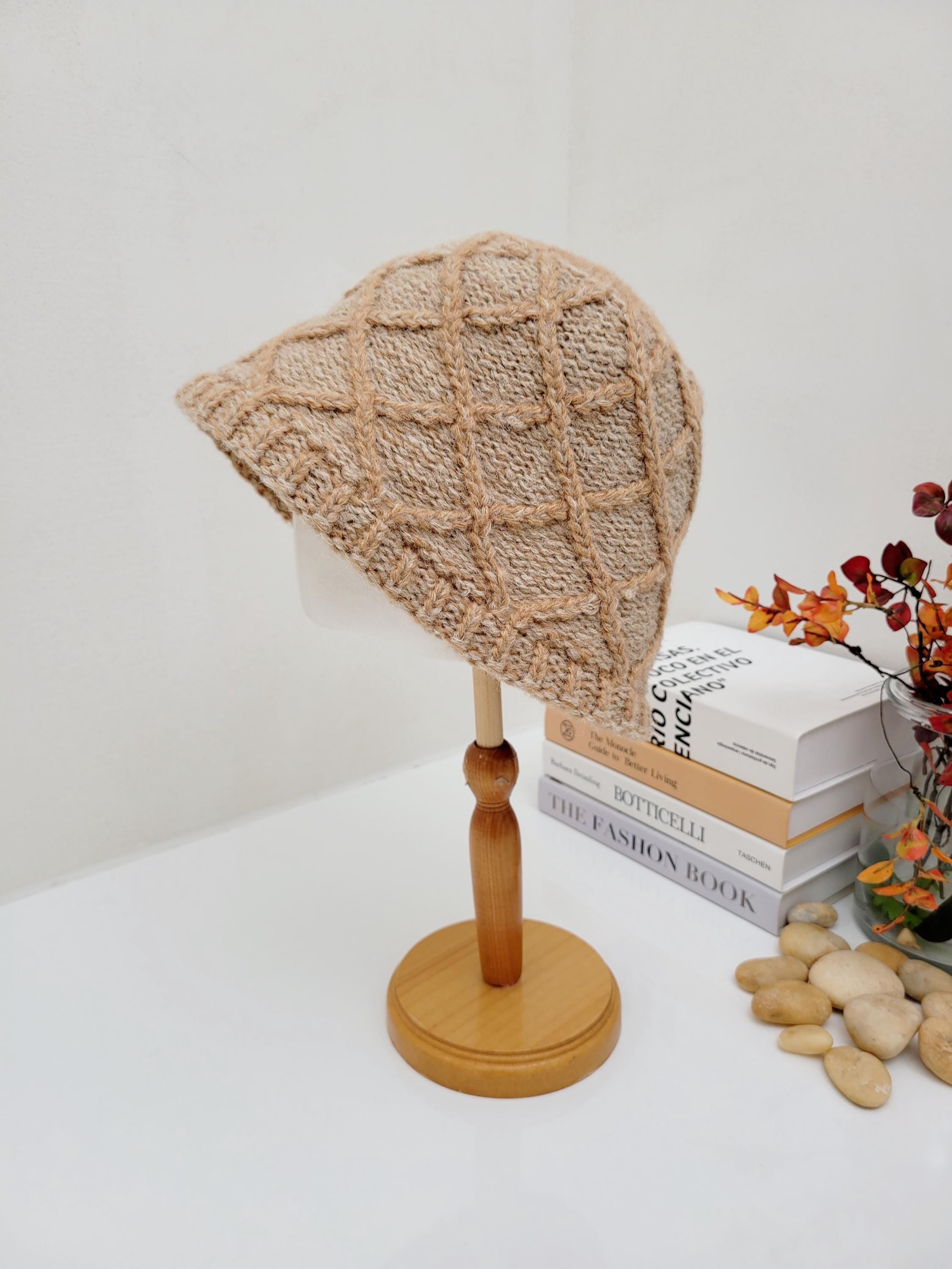 Beige "winter in the paris" knit hat with a grid pattern, displayed on a wooden stand
