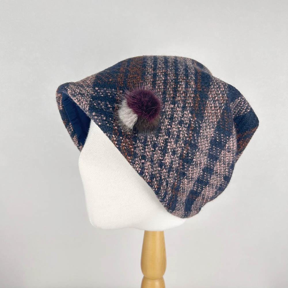 Brown and blue checkered slouch beret with a fluffy pom-pom detail. A stylish chekered slouch hat.