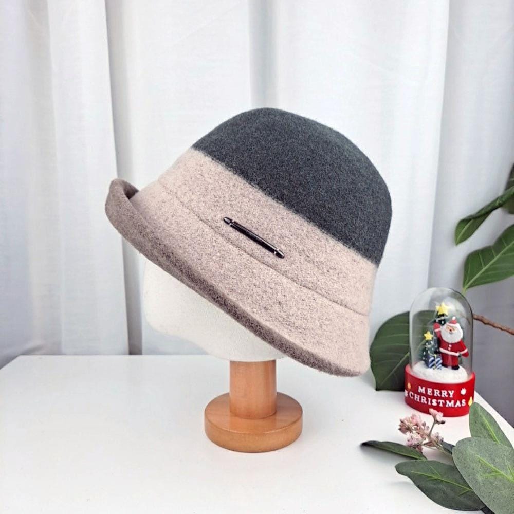 3tone wool bucket hat in gray and beige felt, displayed on a wooden stand. A stylish and warm accessory.