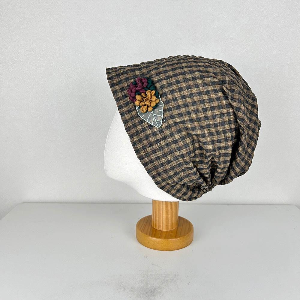 Brown and black checkered beanie hat with floral detail. A stylish chekered beanie for everyday wear.