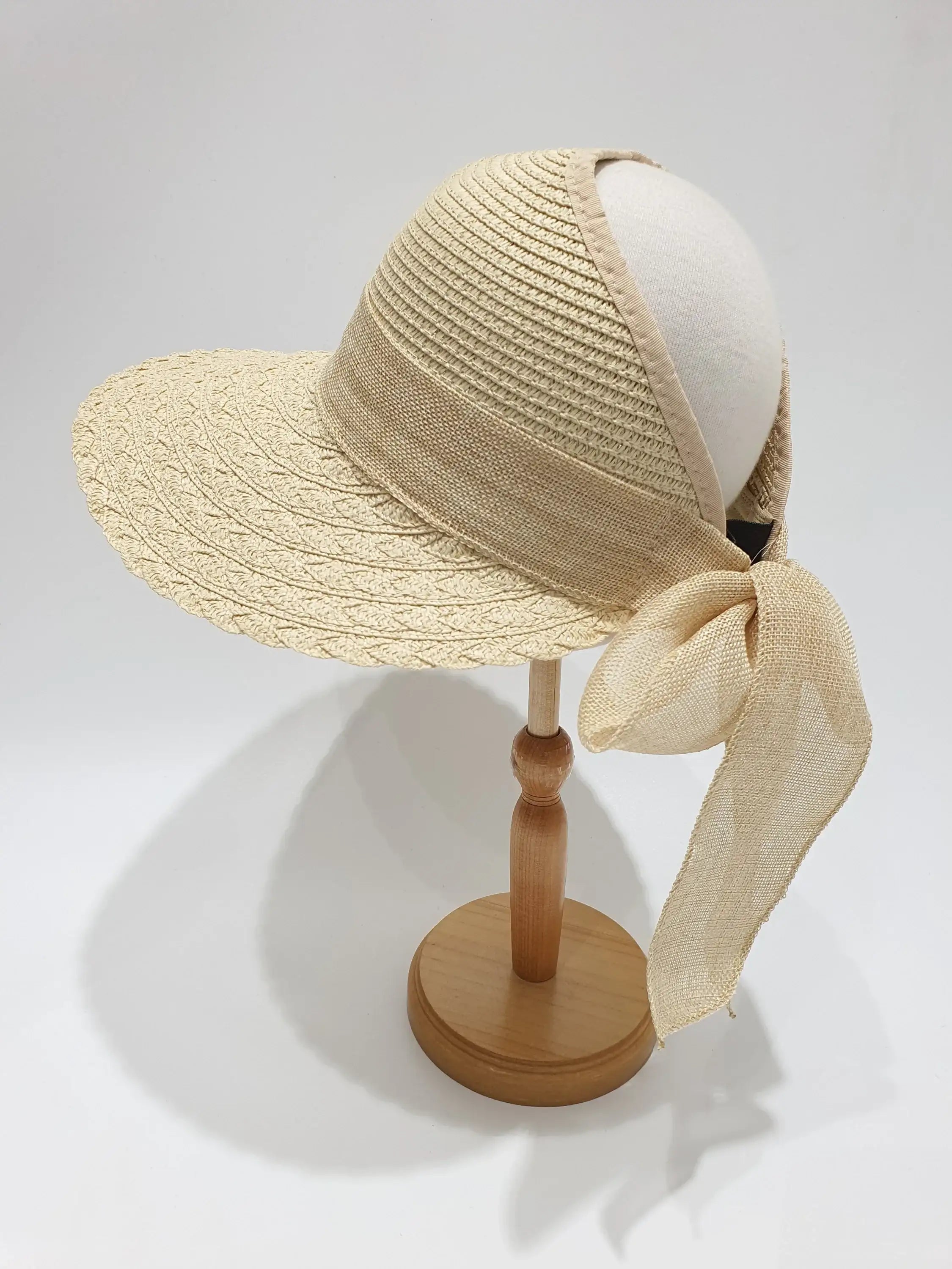 the big island straw sun visor on a stand; a beige woven hat with ribbon detail, perfect for summer vacation